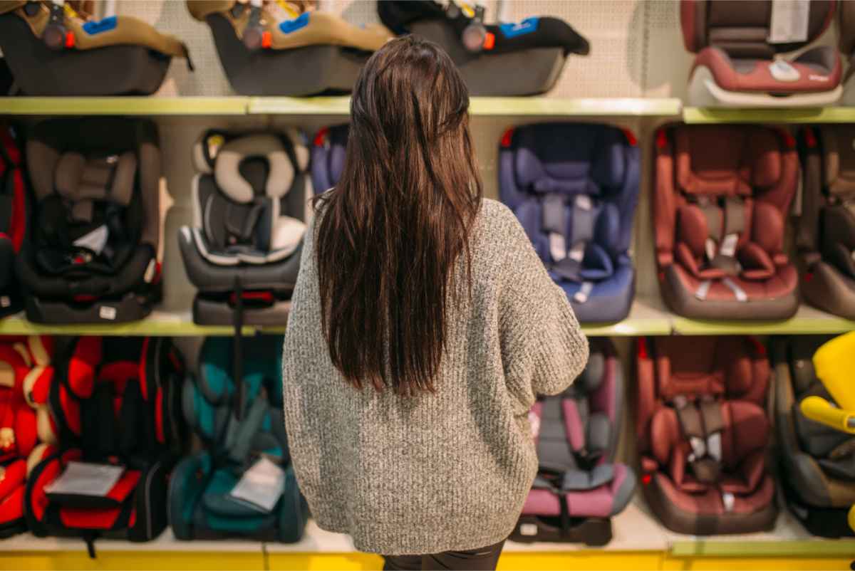 Vrouw voor een rij kinderzitjes in een winkel