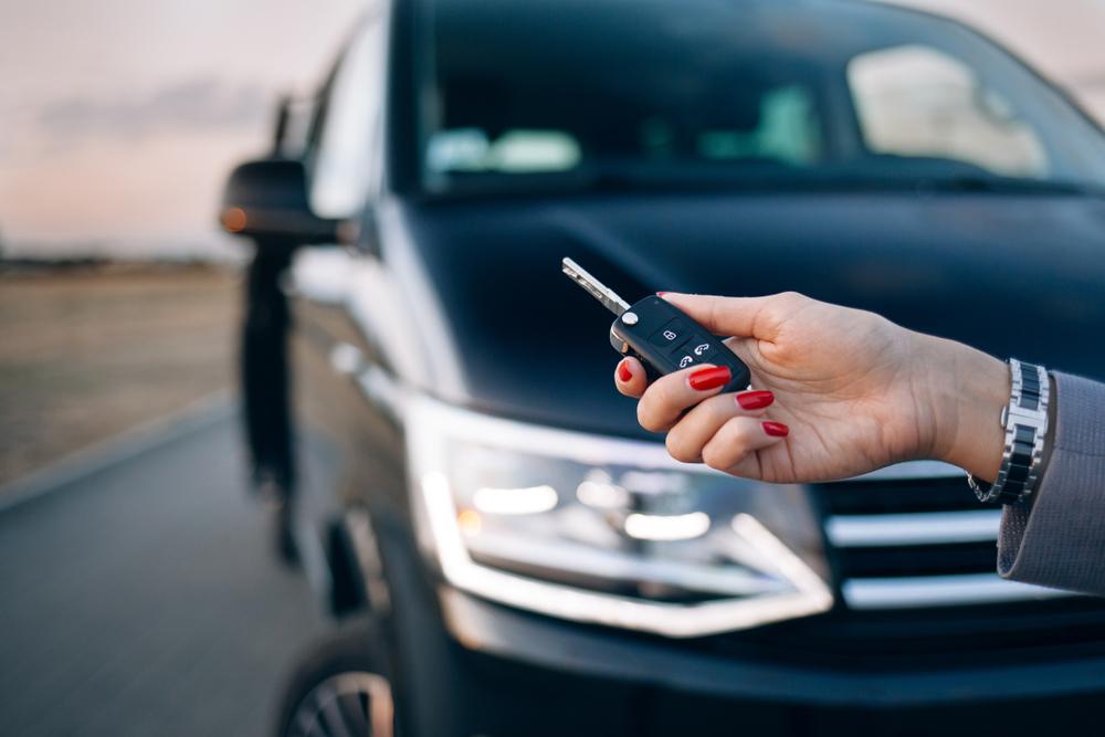 Vrouw die de sleutel van haar huurvoertuig vasthoudt